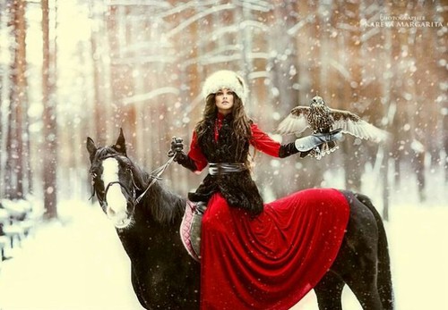 девушка в красном на коне с соколом в руке в зимнем атмосферном лесу