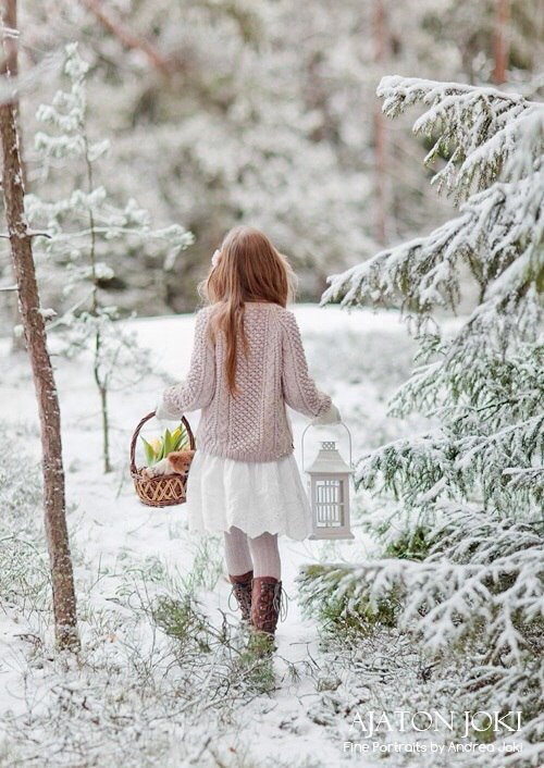 рыжая девочка со спины идет в лес в руках корзинка с плюшевым мишкой и подсвечник в виде фонаря справа от девочки елочка в снегу