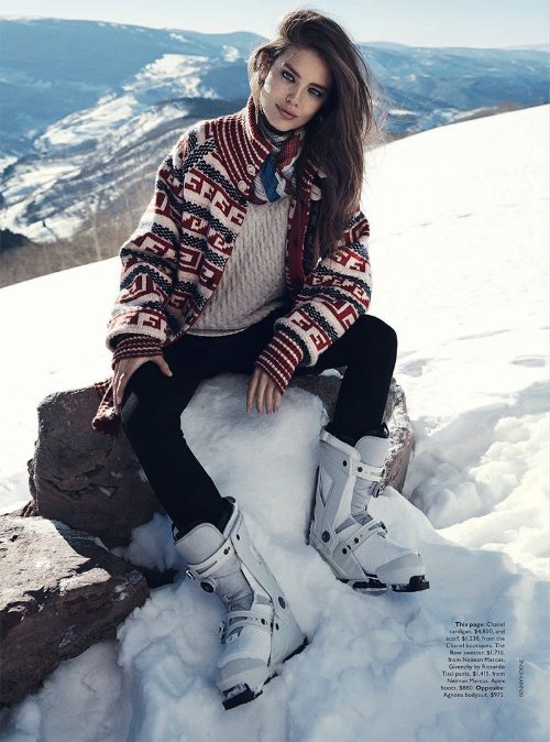 девушка с коричневыми волосами в свитере с орнаментом сидит на камне в зимних горах