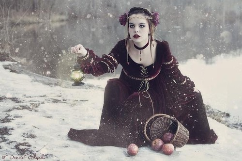 девушка в образе принцессы присела собрать яблоки которые выпали из корзинки на снегу