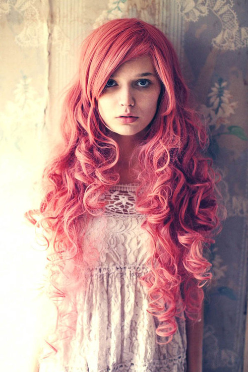 девушка Лолита в кружевном платье и длинными кучерявыми волосами стоит у стены