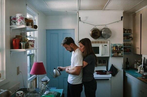 влюбленная пара на кухне, он готовит чай, она обнимает его сзади