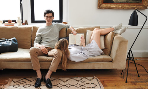 мужчина в очках сидит на диване у него на ноге лежит девушка, которая читает книгу