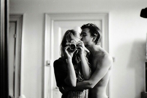 девушка фотографирует в зеркале селфи как её целует в щеку любимый молодой человек