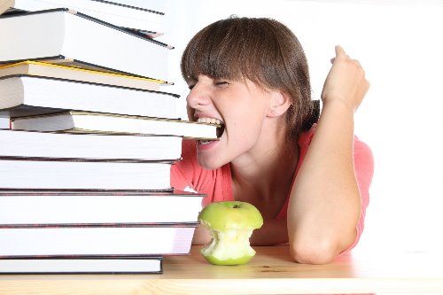 девушка с коричневыми волосами кусает книгу рядом лежит зеленое погрызенное яблоко