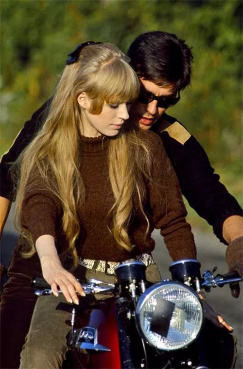 Мужчина учит женщину езде на мотоцикле.