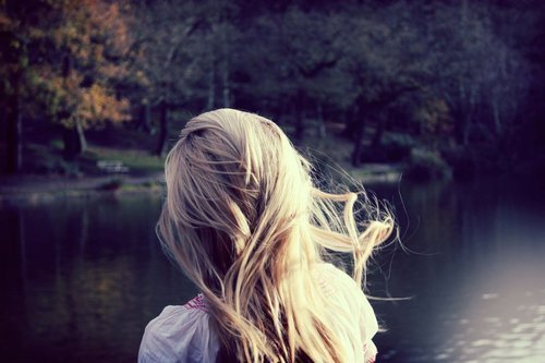 Девушка со светлыми волосами у озера спиной