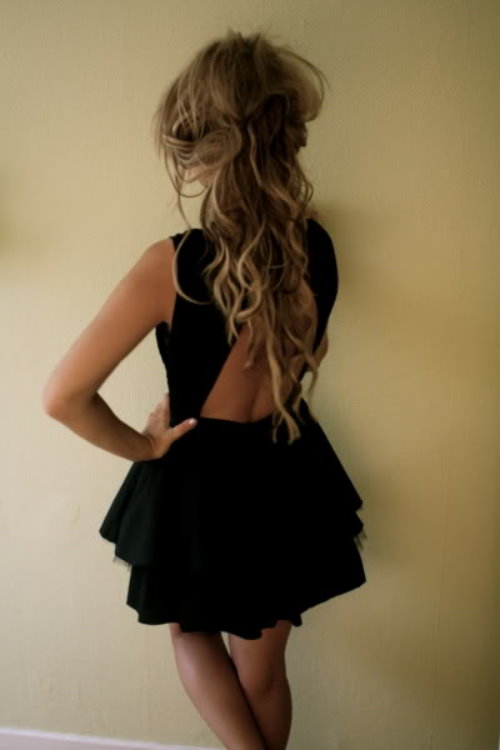 Девушка в черном платье со спины у стены дома