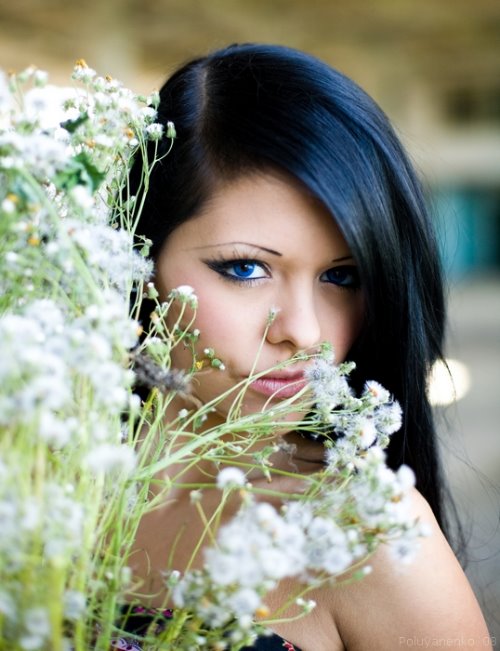 Брюнетка с синими глазами прячется за цветами