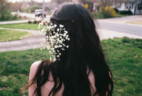 Черные волосы у девушки со спины с белым цветком