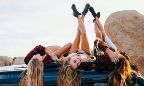 Три девушки на крыше автомобиля подняли вверх ноги