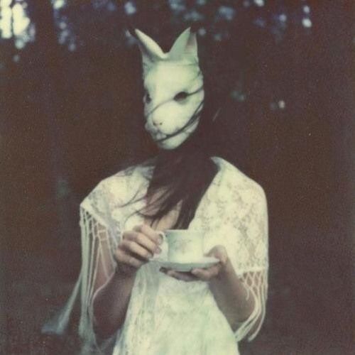 Девушка в лесу в пугающей маске кролика с чашкой чая