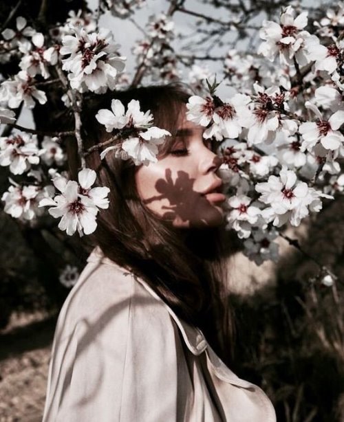 Девушка вдыхает ароматы цветущего дерева