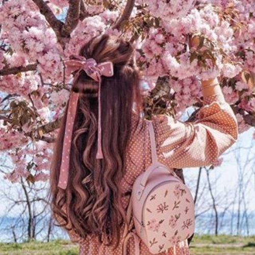 Девушка с розовым бантом укутана цветением сакуры