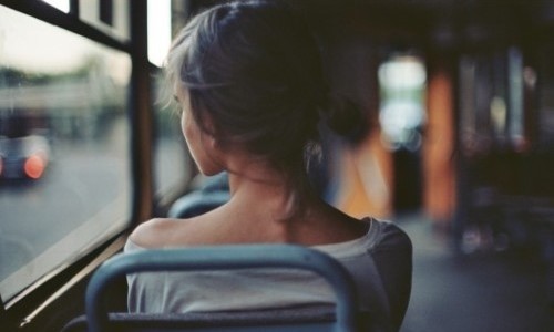девушка с коротким хвостиком смотрит в окно трамвая