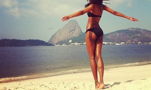 девушка с длинными ногами спиной в купальнике на берегу моря