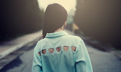 Фото брюнетки спиной в голубой рубашке с вырезанными сердечками