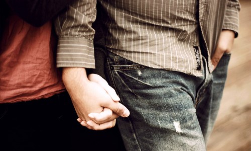 парень держит девушку за руку в джинсах