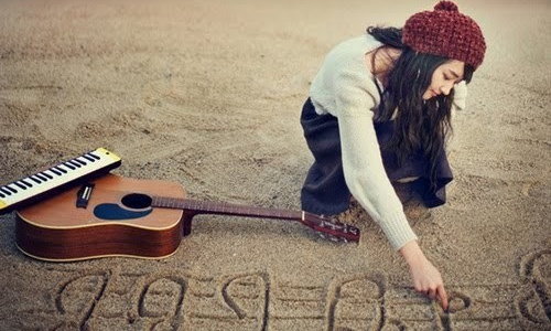 девушка с гитарой рисует ноты на мокром песке