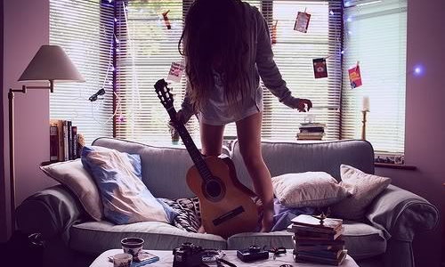 девушка с гитарой прыгает на диване
