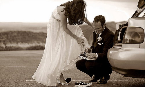 невеста снимает туфли и одевает кеды, жених ей помогает
