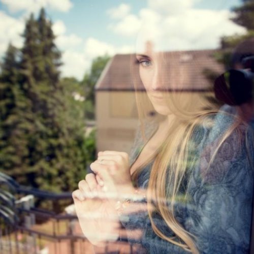 отражение девушки в окне летом на фоне дома