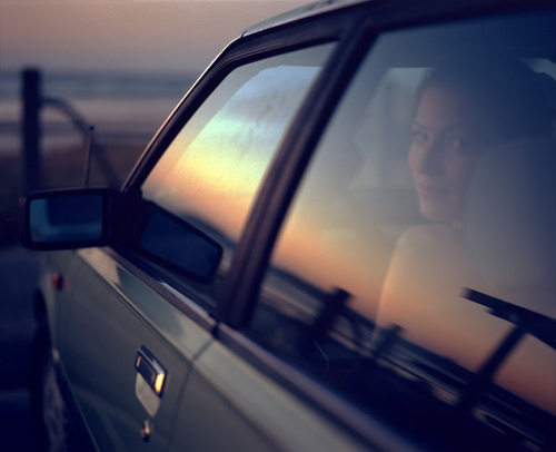 девушка за рулем на закате солнца отражается в окне автомобиля