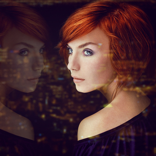 рыжая девушка с голубыми глазами отражается в окне ночного города