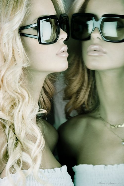 шикарная блондинка в солнцезащитных очках перед зеркалом