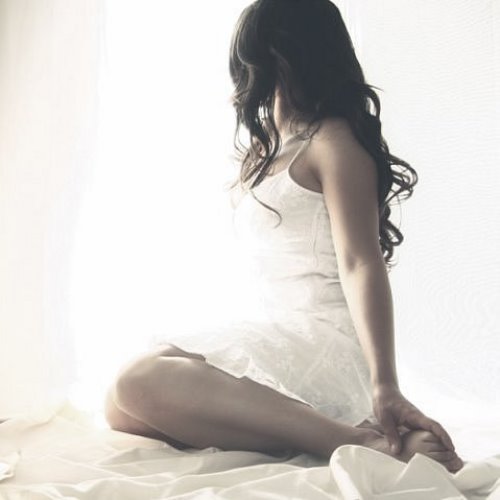 Девушка с длинными черными волосами в белом платье сидит