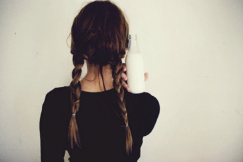 Девушка спиной с бутылкой молока и двумя косичками