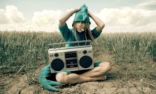 девушка в костюме динозавра в пшеничном поле с магнитофоном на коленях