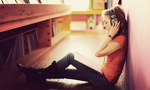 девушка на полу в библиотеке слушает музыку в наушниках