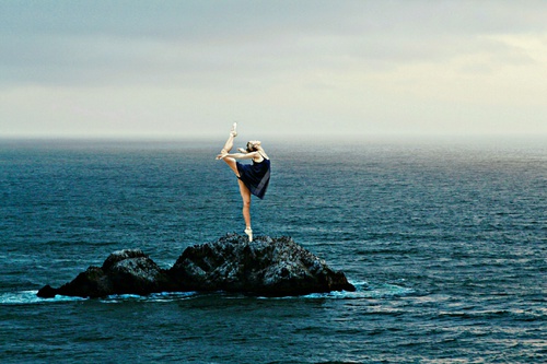 девушка танцует на камне среди моря