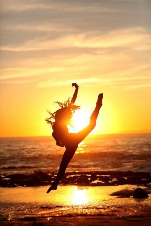 силуэт девушки в лучах солнца прыгающей в танце на море