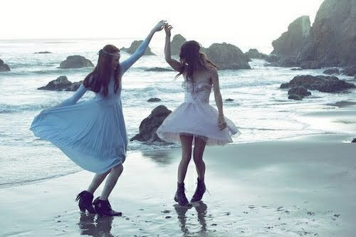 две девушки взявшись за руки танцуют на море