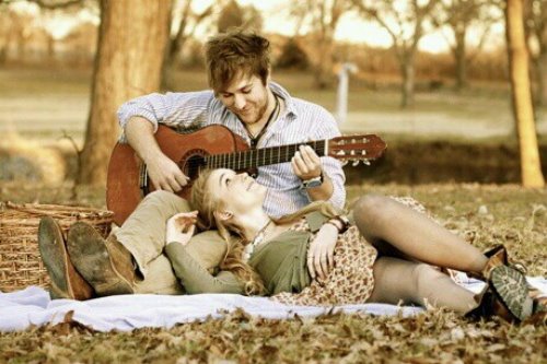 девушка лежит на ногах парня, а он играет ей на гитаре в осеннем лесу