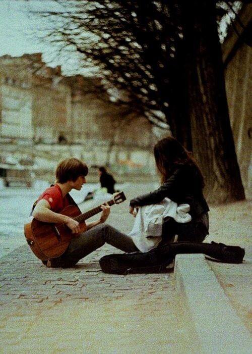 парень играет для девушки на гитаре осенью на улице