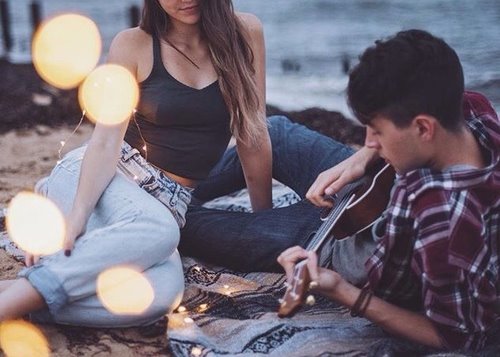 влюбленная пара на берегу играет на гитаре