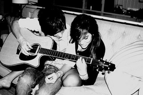 парень с девушкой вместе играют на гитаре