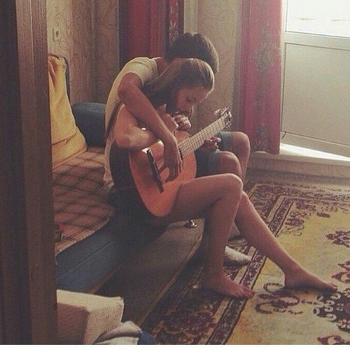 парень учит девушку играть на гитаре