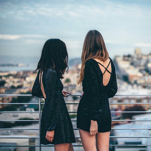 две девушки в маленьких черных платьях без лица на балконе