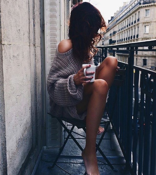 девушка сидит на балконе в свитере без лица с кружкой