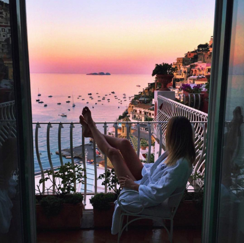 девушка закинула ноги на балкон любуется закатом на море без лица