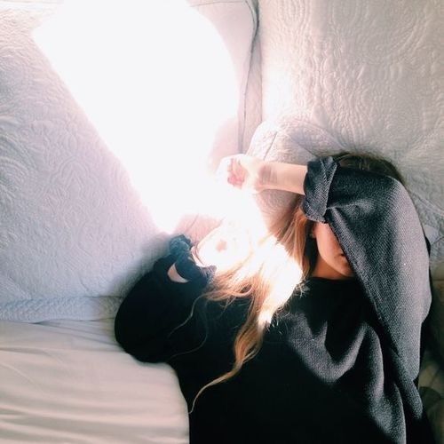 девушка в мужском свитере в кровати без лица в лучах солнца