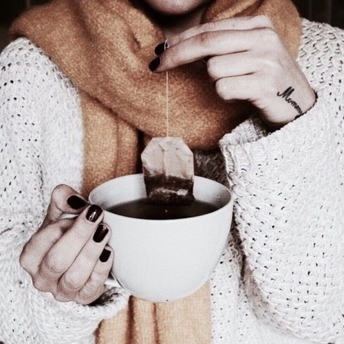 девушка в теплом свитере и шарфе заваривает чай