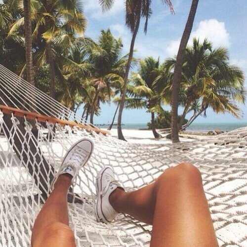 ноги девушки без лица в гамаке среди пальм на море летом