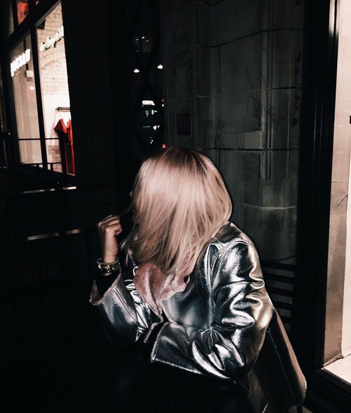 девушка в серебряной куртке сидит в кафе без лица