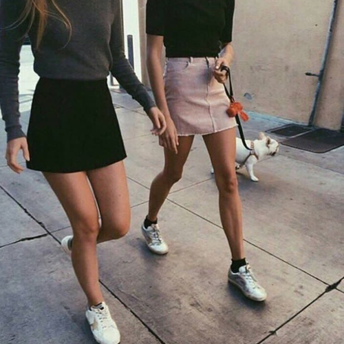 две девушки в юбках гуляют с собакой