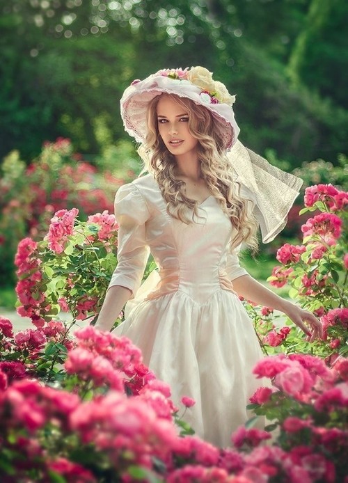 красивая девушка как принцесса в саду в шляпке и шелковом платье